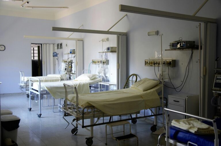 Three hospital beds laid out in a row in a room surrounded by medical equipment.