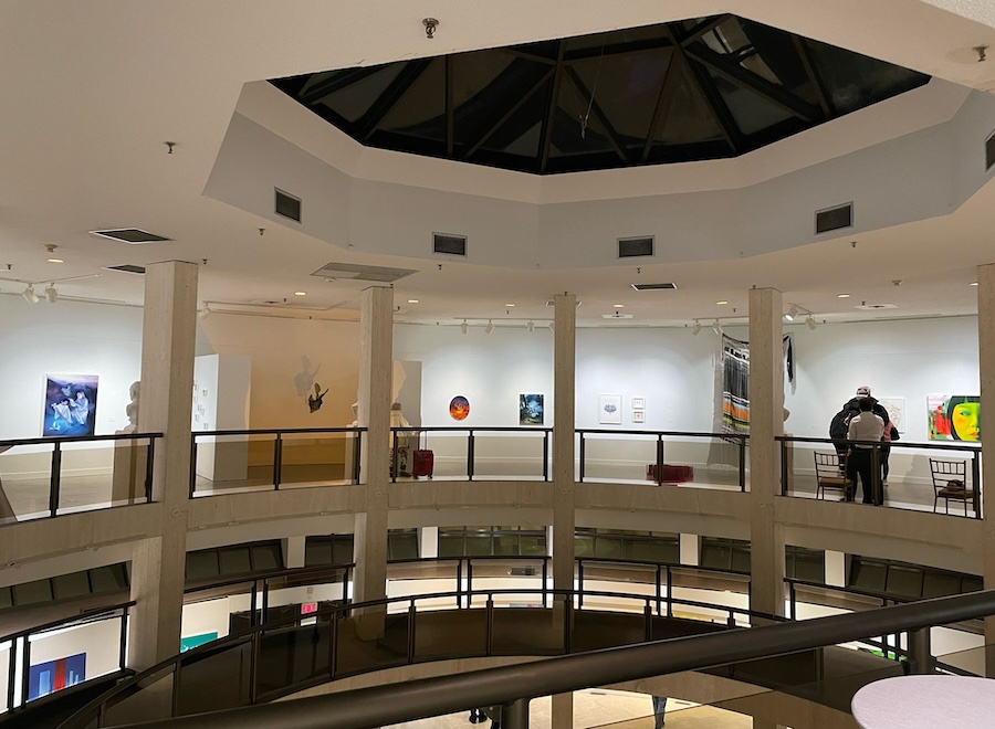 Inside of building with three levels and art hanging on its white walls.
