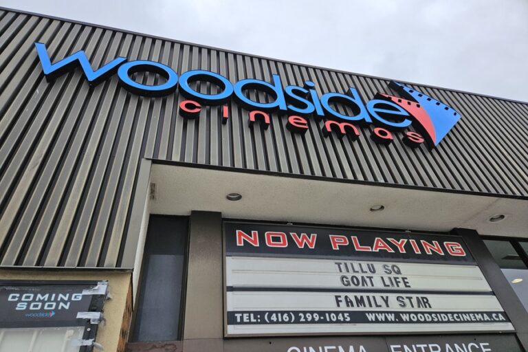 A photo of the outside of a Toronto Cinema Hall with a NOW Playing sign.