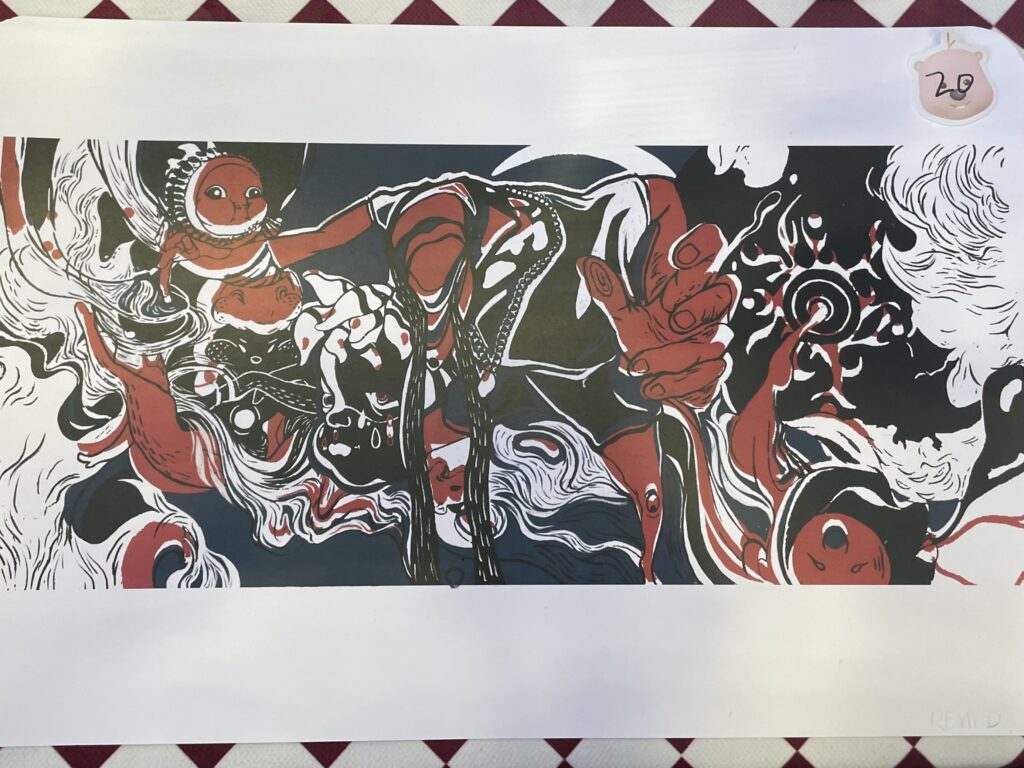 A black, red and white abstract drawing done on paper sits for sale on a table.