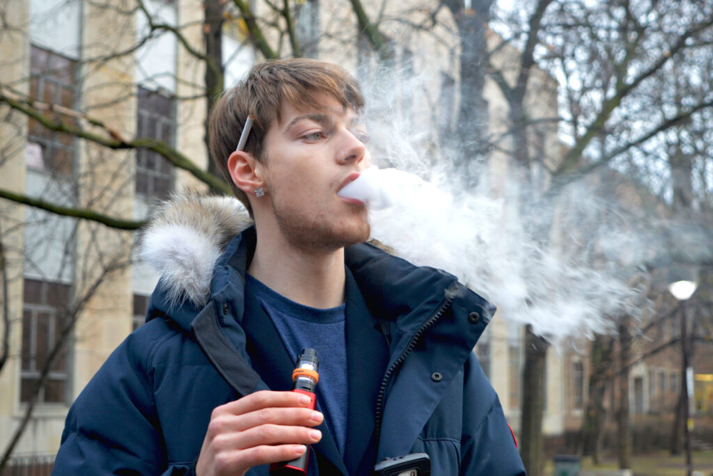 A person vaping and blowing out smoke.