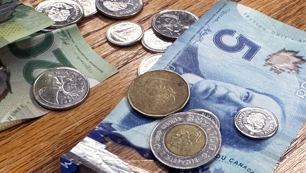 A photo of Canadian money spread out on a wooden table.