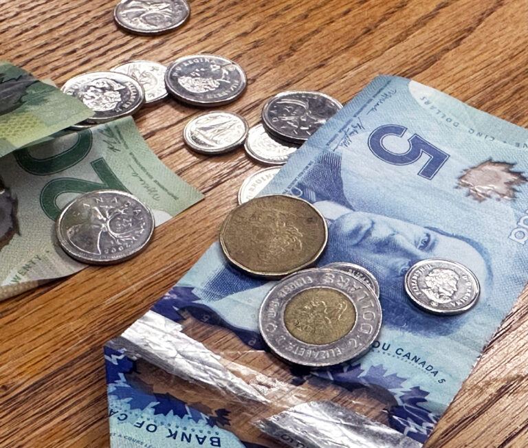 A photo of Canadian money spread out on a wooden table.