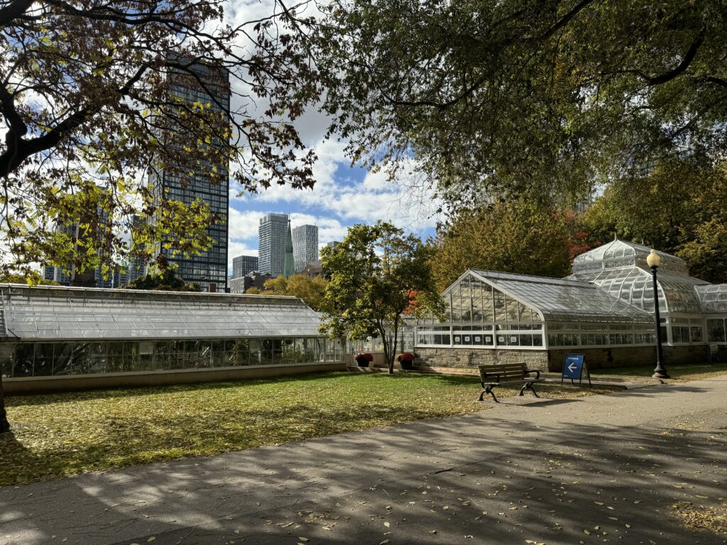 A landscape shot of a park with a glass ceiling conservatory