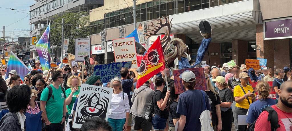 Protestors, signs reading "Justice for Grassy Narrows", and a Caribou puppet on Dundas st.