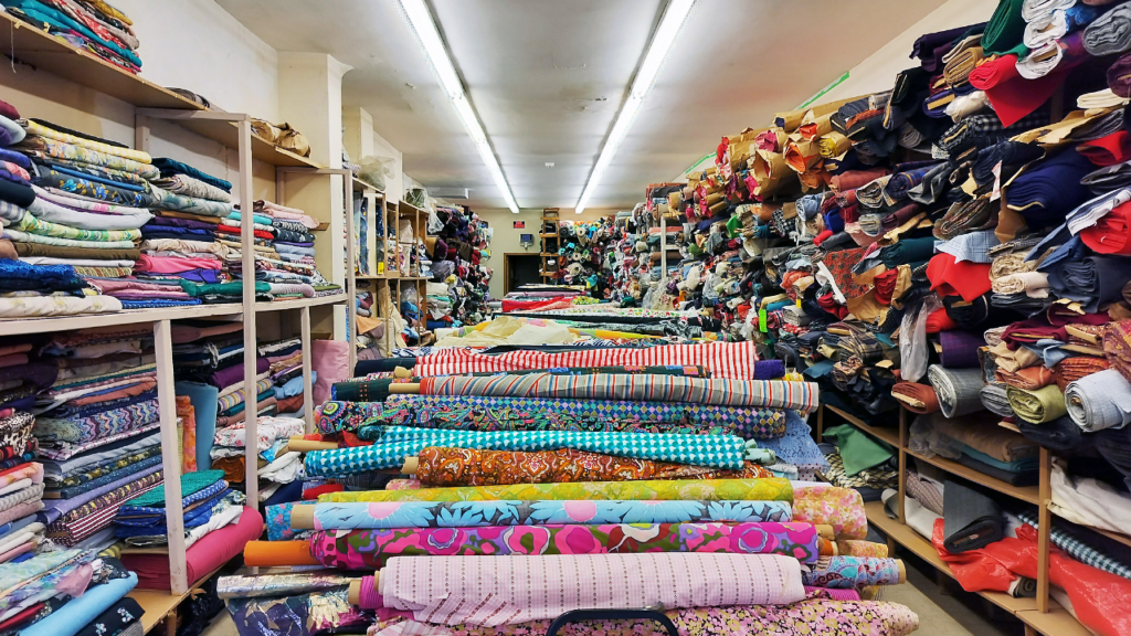 A photo of fabrics rolled up and laid out on tables in a store.