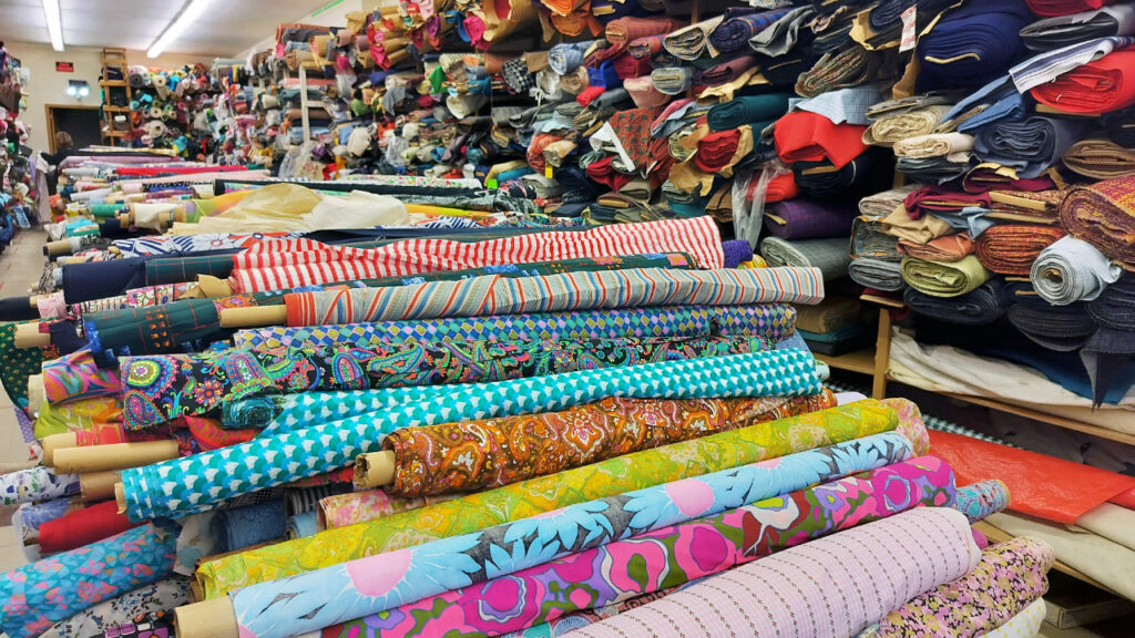 A photo of fabrics rolled up and laid out on tables in a store.