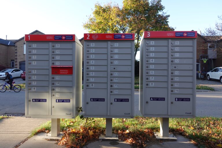 Three red and grey mailbox lockers on a street.