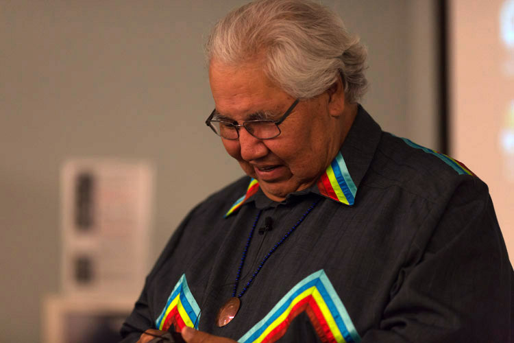 Murray Sinclair stands against a blurred background, holding a handheld radio.