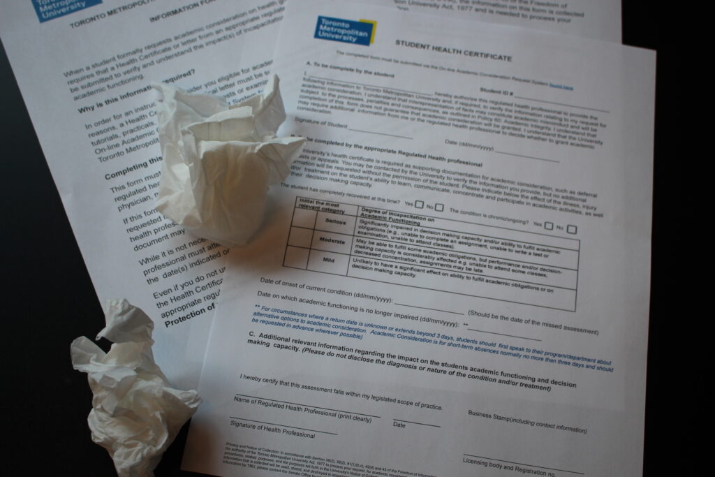 Crumpled up tissues on top of sick note forms.