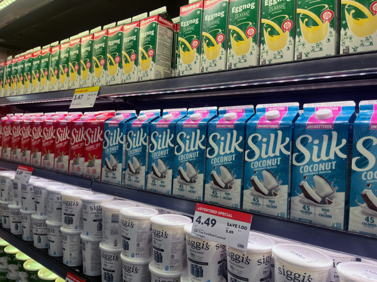 Shelves of refrigerated products at a grocery store. Products include plant-based Silk milk.