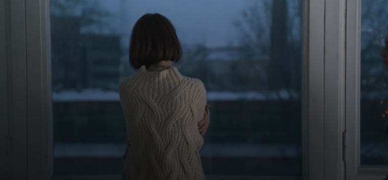 A woman facing a window.