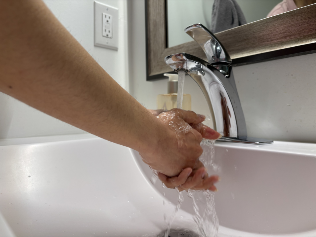 Student washing her hands in the bathroom.