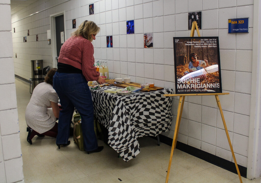 Two women setting up a snack table in a hallway.