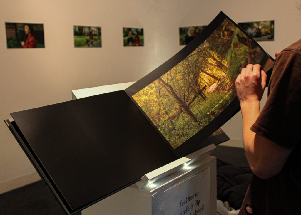 Hands flipping through a large photobook with a picture of the forest.