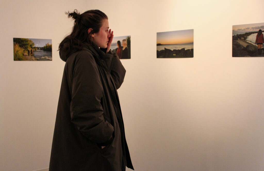 A person wipes away tears while looking at photos on a wall.