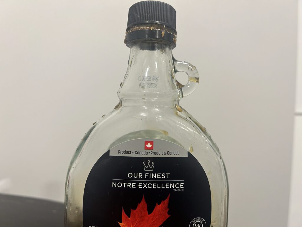 A photo of a maple syrup bottle with label with a maple leaf on it.