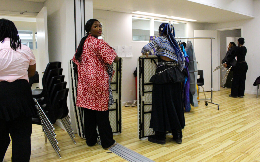 Two women hold folded up tables in a room