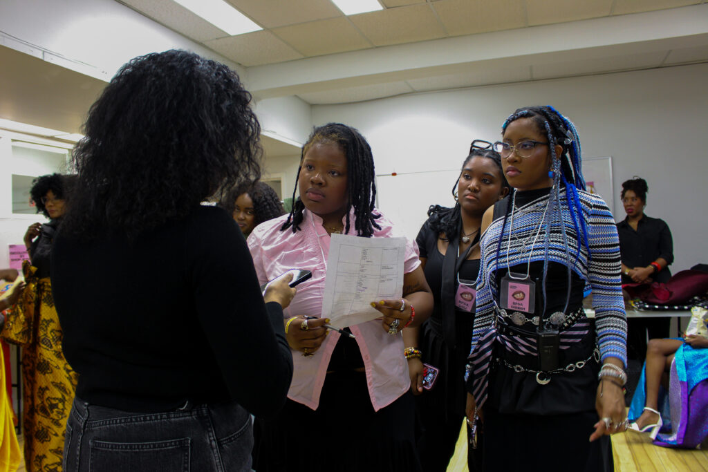 Three women listen to a woman in a black shirt speak