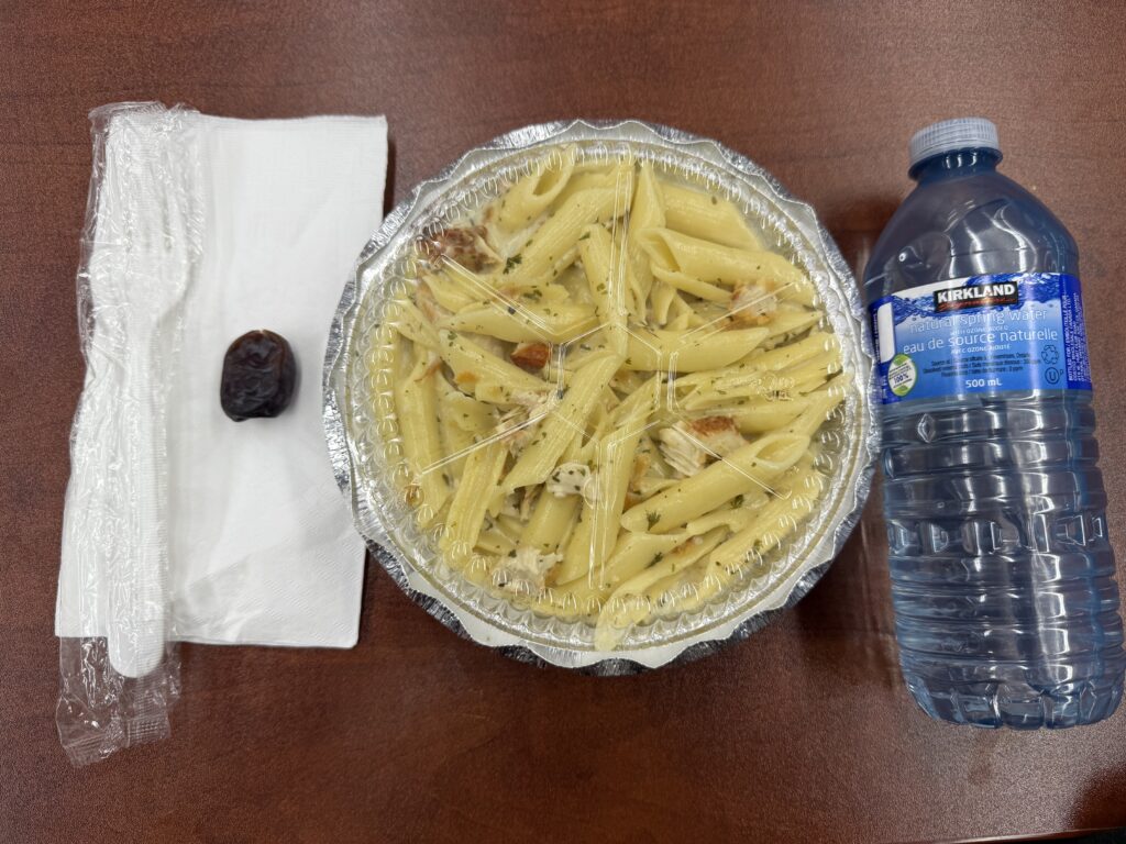 A date on the left on top of a napkin. In the middle is a container of food and on the right side is a water bottle