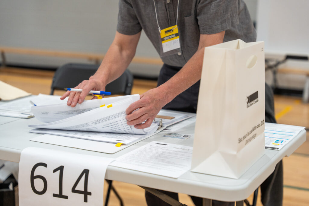A photo of a poll worker laying out papers on a table.