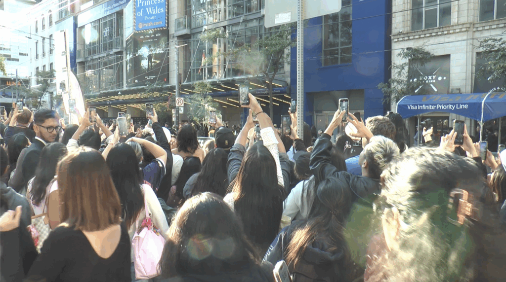 Crowds of people at the 2025 Toronto International Film Festival record with their phones high above their head.  