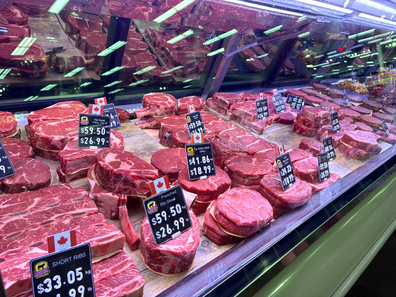 Raw beef on display behind glass with prominent Canadian flags for the locally sourced meat.