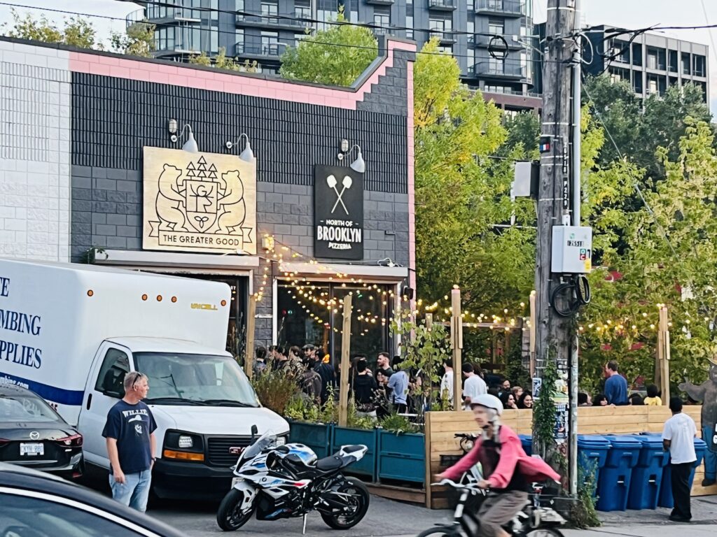 A restaurant with crowded patio and truck and motorbike outside.
