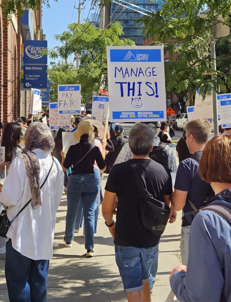 A photo of protesters holding signs in front of George Brown campus.