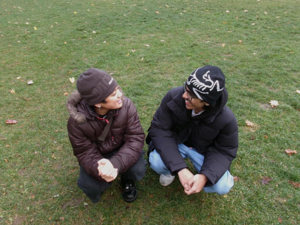 Two people smiling at each other on a field of grass
