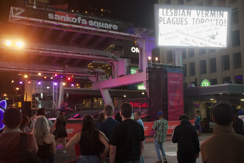 A group of people at Sankofa Square facing a stage where a DJ is playing for Nuit Blanche.