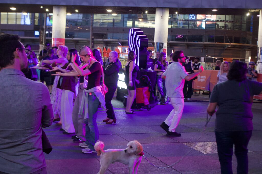 People dancing at Sankofa Square during Nuit Blanche. One person has a dog on a leash.