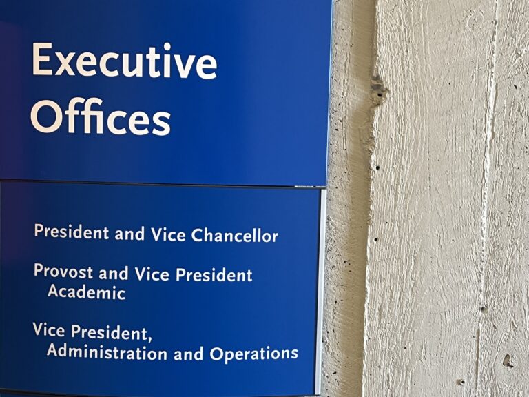Blue sign with white letters that display where some executives offices are located at the TMU campus.