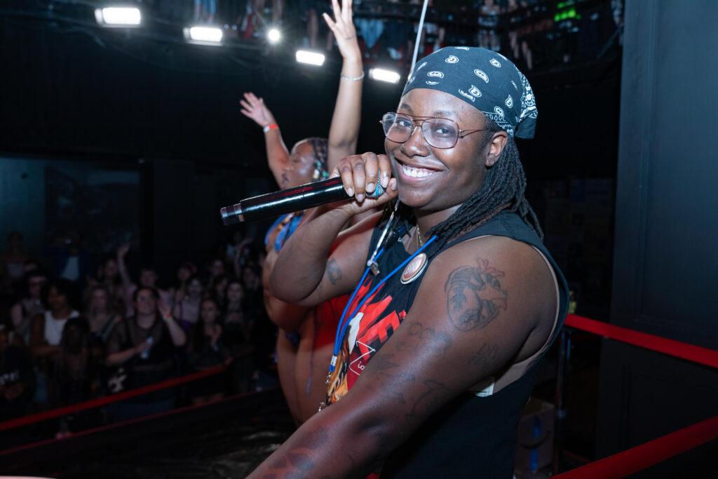 AMODIO-QUEERLONELINESS This is a photo of a woman smiling and holding a microphone.
