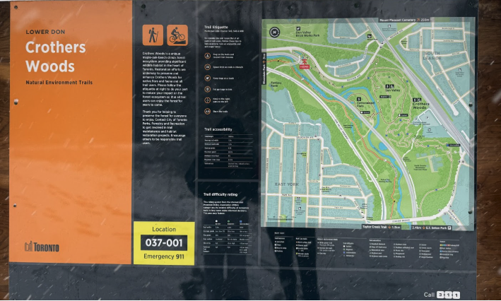 An outdoor information black and orange board titled “Lower Don Crothers Woods Natural Environment Trails.” The sign includes a detailed trail map showing routes through the Don Valley, accessibility and difficulty ratings and trail etiquette icons. 