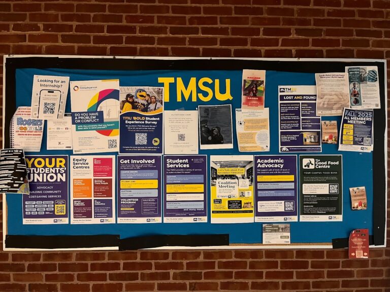 Bulletin board against a brick wall full of colourful posters.