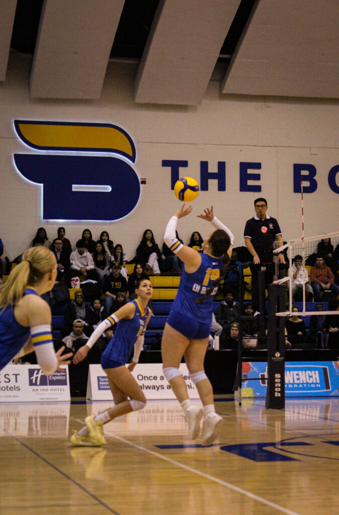A women's volleyball player pushes the ball in the air during a game.
