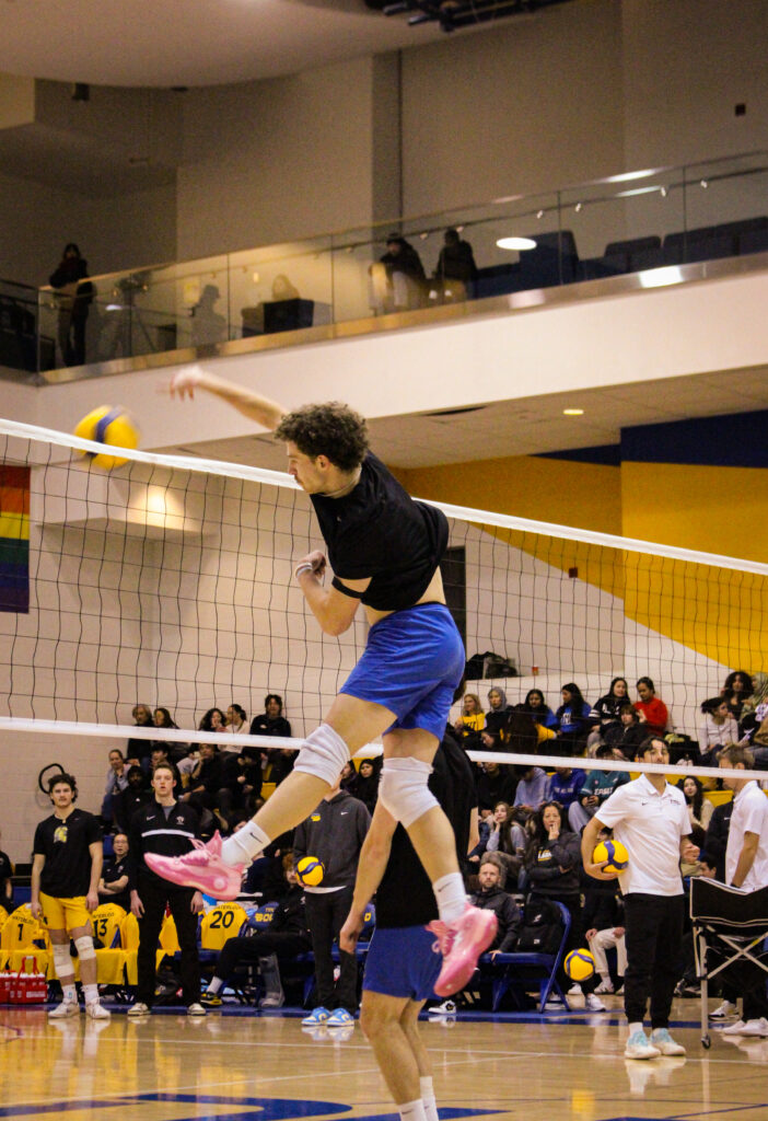 A men's volleyball player in the motion of hitting a ball.