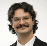 Headshot of a smiling man with a mustache and glasses.