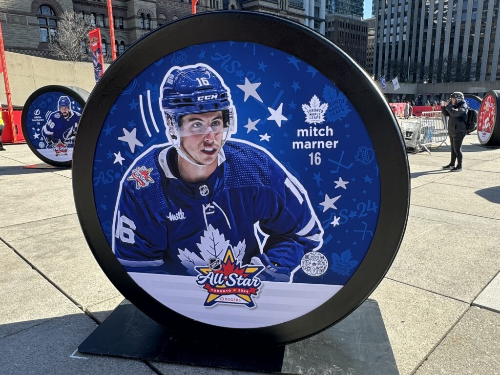 A large circular outdoor display of Mitch Marner in a Toronto Maple Leafs jersey, with his name, number 16 and NHL All-Star Toronto 2024 branding.