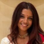 A photo of a person in a red and white sari.