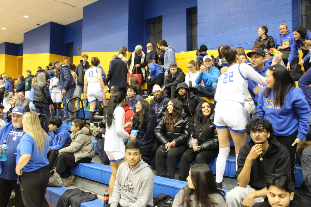 Basketball players celebrating with supporters after a game.