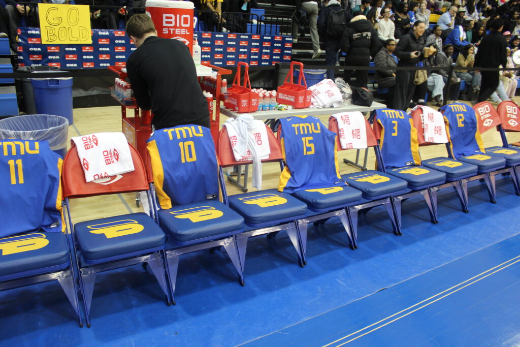 Basketball jerseys rest on a set of chairs.