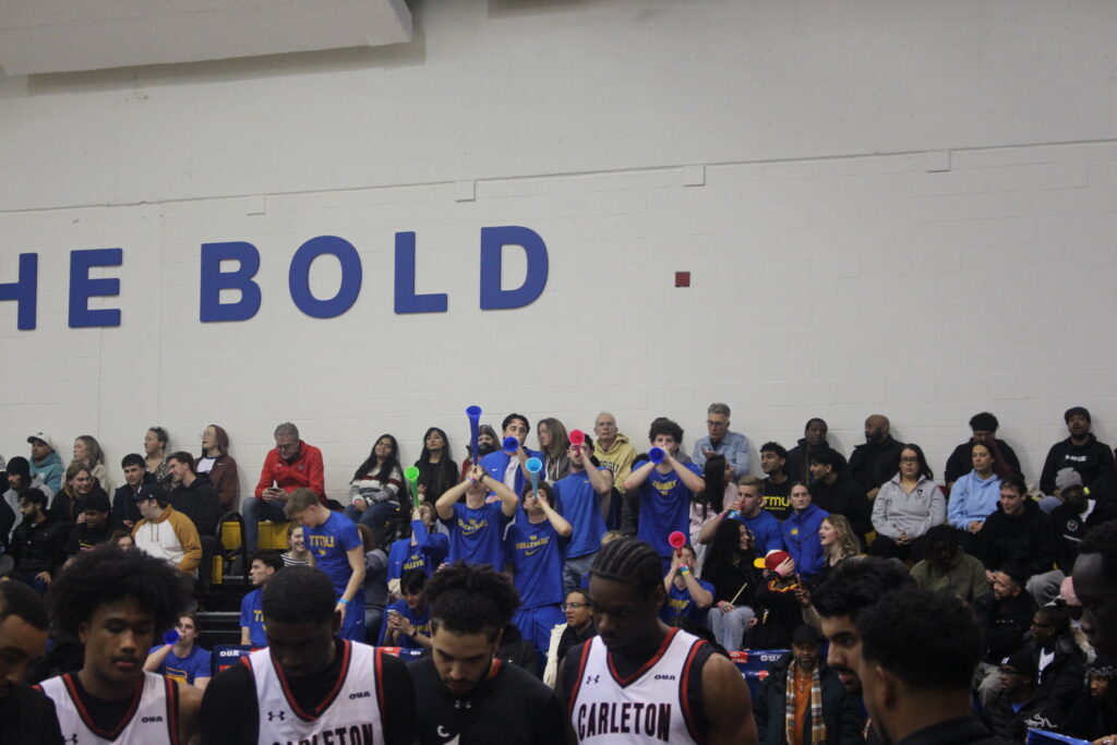 Supporters blow horns at an opposing basketball team.