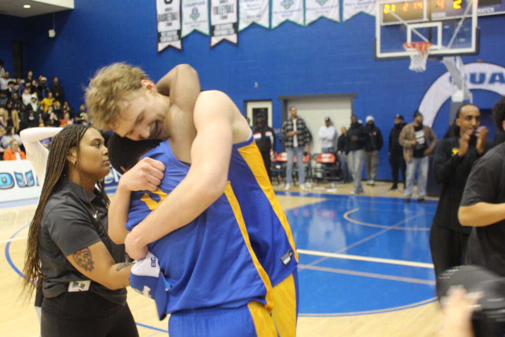 Two basketball players hug after winning a game.