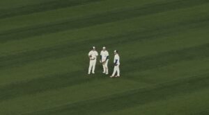 Three baseball players standing in the middle of a baseball field
