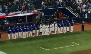 Baseball players standing in a line during the national anthems. 