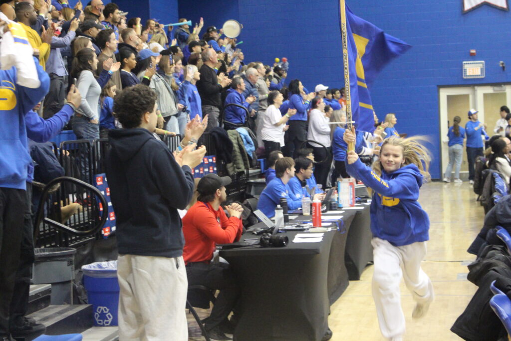 A woman runs with a flag during a basketball game.