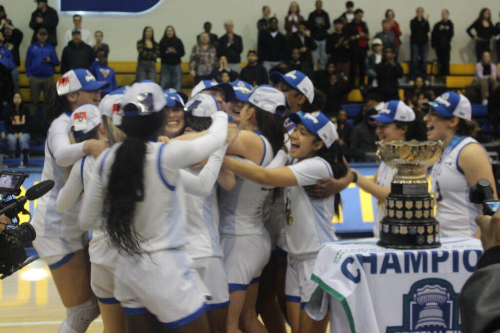 A basketball team hugs each other after winning a trophy. 