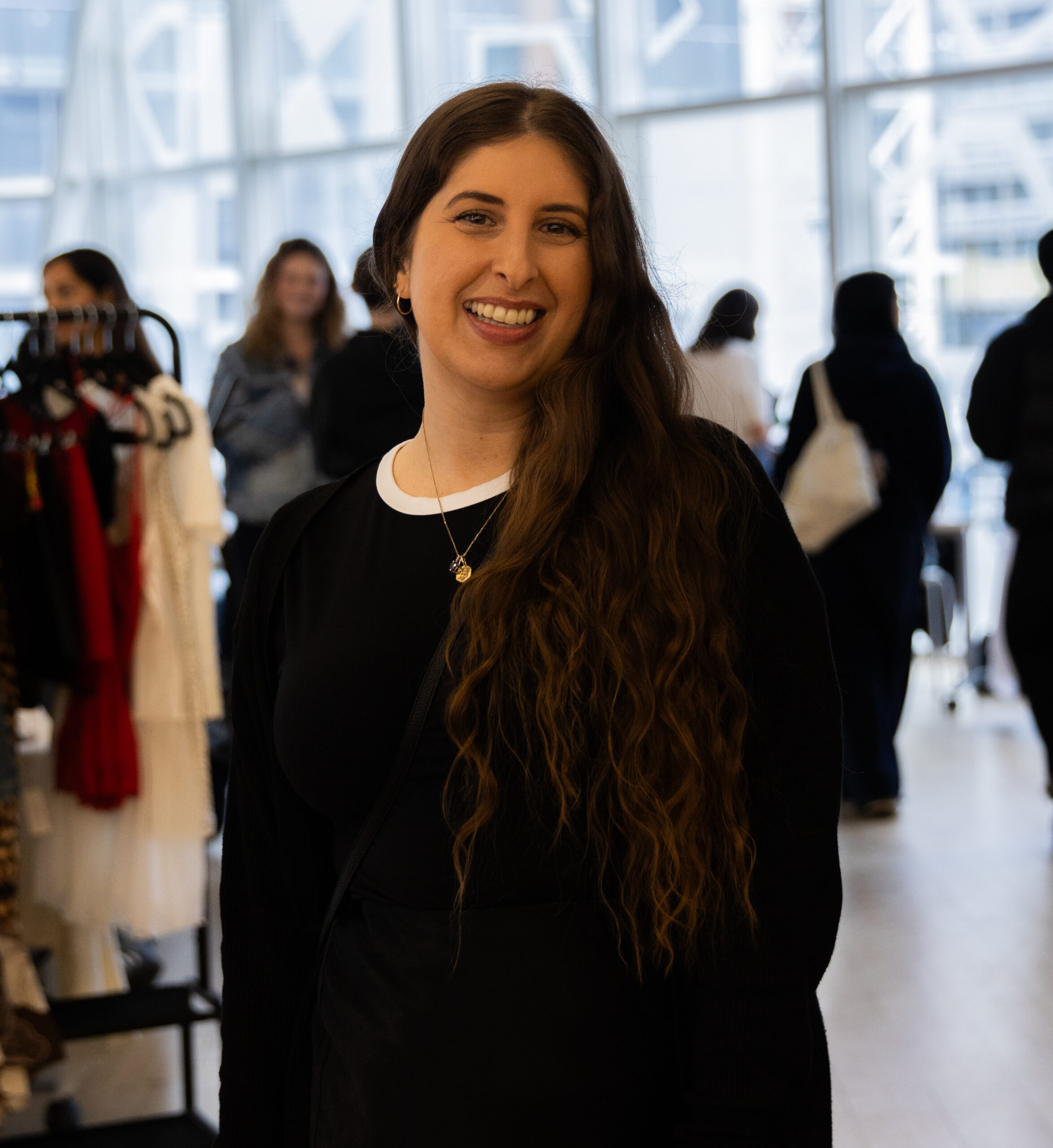 Woman standing in front of a camera wearing black and smiling.